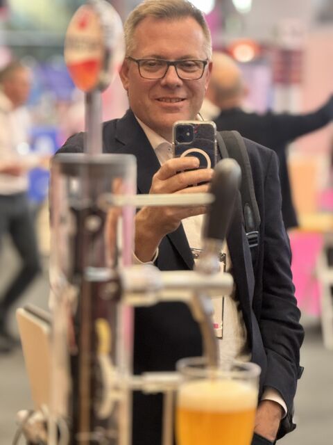 Guest grinning as he films his freshly poured beer at Homer on the Money20/20 stand.