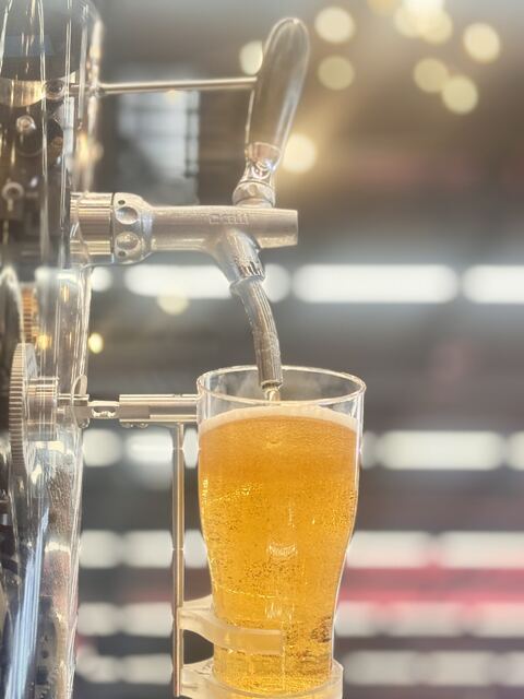 Full glass under the tap with bokeh lights behind.